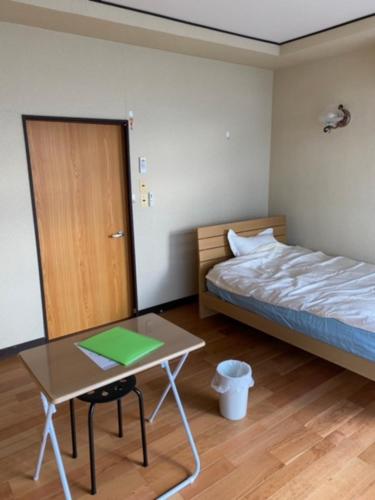 een slaapkamer met een bed, een tafel en een bureau bij 民泊ドリームルーカー in Haranomachi