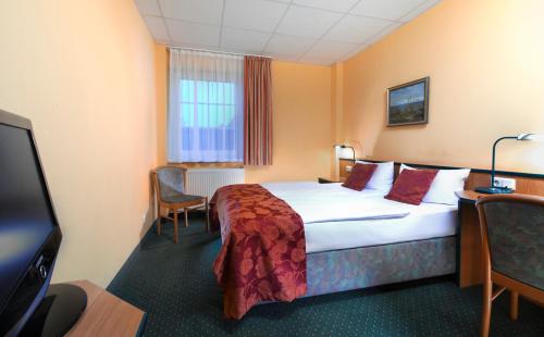 a hotel room with a bed and a flat screen tv at Hotel Landhaus Dierkow in Rostock