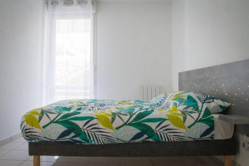ein Bett mit einer bunten Bettdecke und einem Fenster in der Unterkunft L'Olympic in Chalezeule