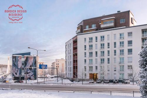 a large white building in the snow next to a street at Nordica Design Residence Rovaniemi in Rovaniemi