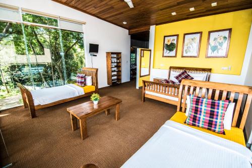 a living room with two beds and a table at Ella Planters Bungalow in Ella