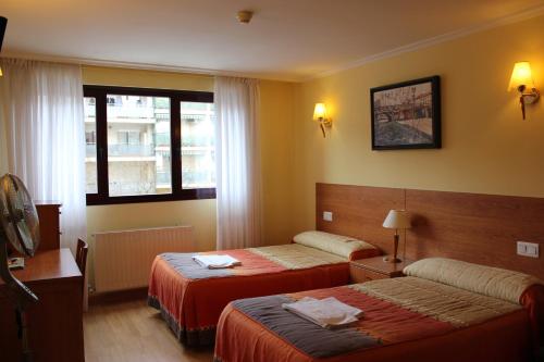 ein Hotelzimmer mit zwei Betten und einem Fenster in der Unterkunft Hostal El Volante in Estella