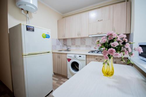 a kitchen with a table with a vase of flowers on it at Алтай 1-6, рядом с аэропортом in Almaty