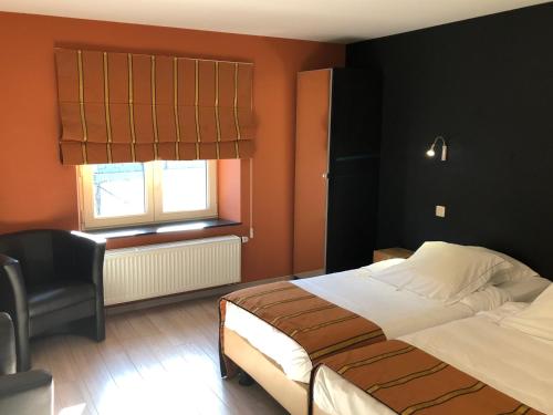 a bedroom with a bed and a chair and a window at Hotel La Librairie in Durbuy