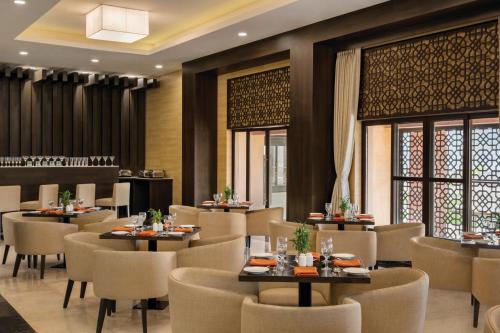a restaurant with tables and chairs and windows at Ramada Encore by Wyndham Statue of Unity in Kevadia