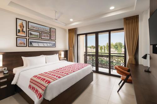 a hotel room with a bed and a balcony at Ramada Encore by Wyndham Statue of Unity in Kevadia