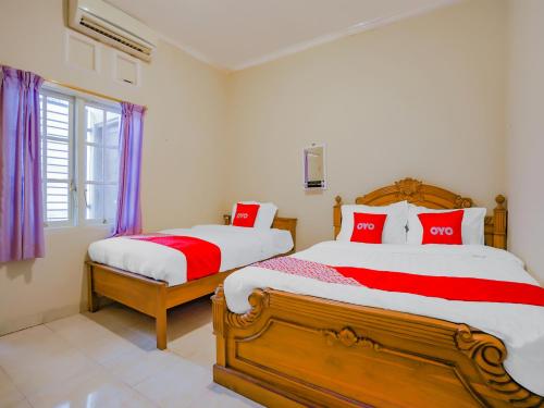 a bedroom with two beds with red and white pillows at Super OYO 90210 Kenari House Syariah in Yogyakarta