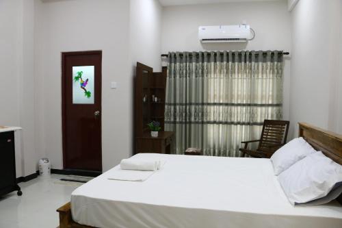 a bedroom with a white bed and a window at Thisha Hotel & Restaurant in Jaffna