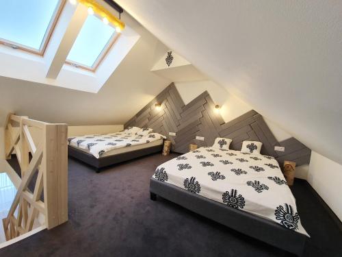 two beds in a attic room with two windows at RelaxApart - Komfortowy apartament Pod Stokiem in Szczyrk