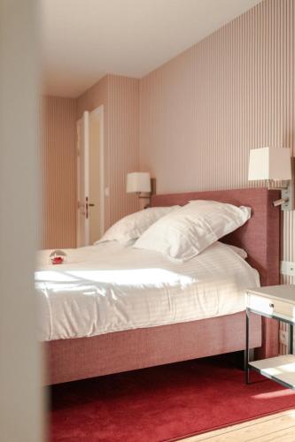 a bedroom with a large bed with white sheets and pillows at Villa Monceau Louvain la neuve in Louvain-la-Neuve