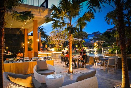 un restaurante con palmeras y gente sentada en las mesas en Kudos Parc Pattaya, en Pattaya South