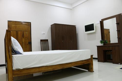 a bed in a room with wooden furniture and a mirror at Thisha Hotel & Restaurant in Jaffna