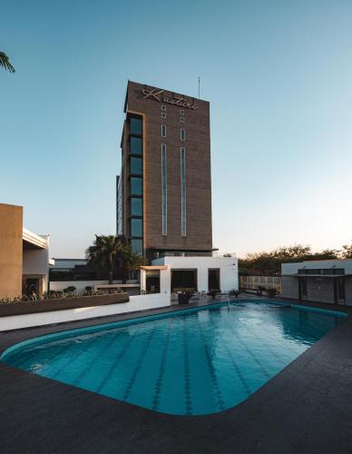 a large swimming pool in front of a tall building at Hotel Kasturi Orchid in Pāl