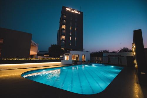 a swimming pool in front of a building at night at Hotel Kasturi Orchid in Pāl