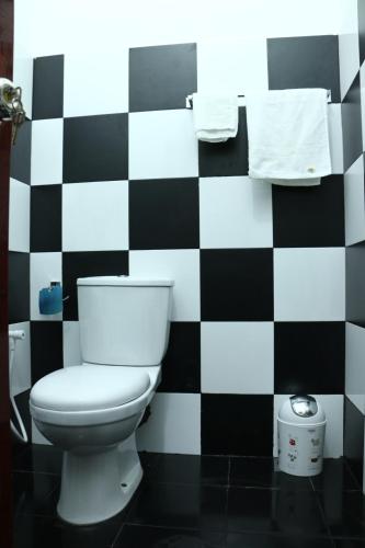 a bathroom with a toilet and a black and white checkered wall at Thisha Hotel & Restaurant in Jaffna