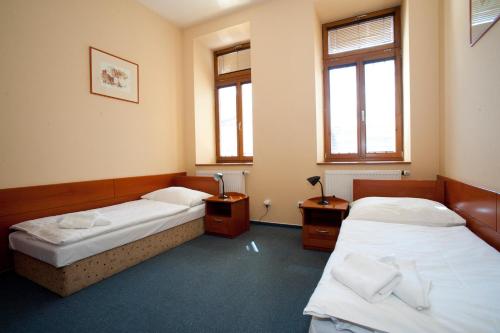 a room with two beds and two windows at Penzion Zelená Žába in Pardubice