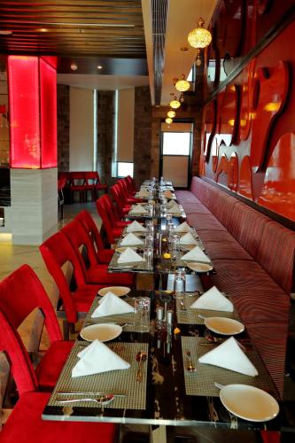 a long table in a restaurant with red chairs at Hotel Kasturi Orchid in Pāl