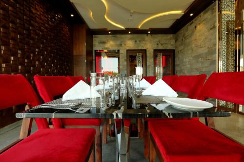 a dining room with a table and red chairs at Hotel Kasturi Orchid in Pāl