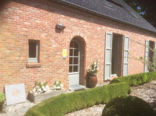 a brick house with a white door and some bushes at B&B De Kastanjeboom in Jabbeke