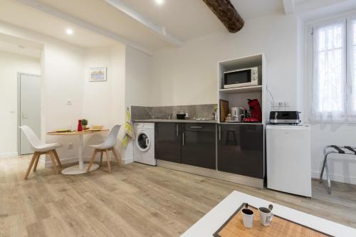 une cuisine avec des armoires noires, une table et des chaises dans l'établissement Cosy Studio in the Old Town - St François Square, à Nice