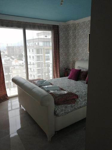 a bedroom with a bed and a large window at Aqua Royal Alexus Luxury Holiday Apartments Girne in Kérynia