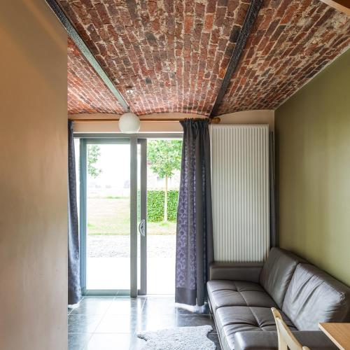 a living room with a couch in front of a door at De Grote Linde in Oostkamp