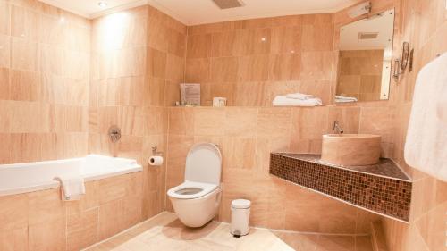 a bathroom with a toilet and a sink and a tub at The Grand Hotel in Swansea