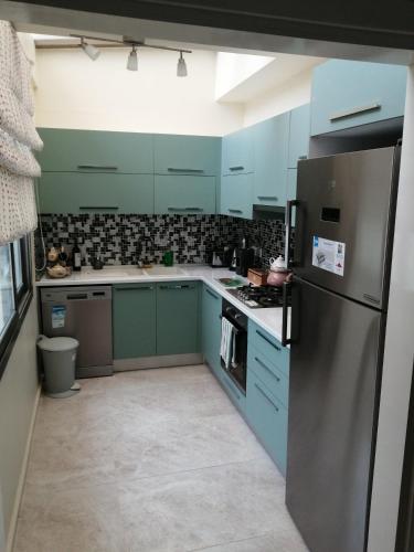 a kitchen with blue cabinets and a stainless steel refrigerator at Aqua Royal Alexus Luxury Holiday Apartments Girne in Kérynia