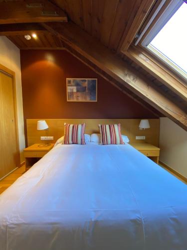 a large white bed in a room with a window at Aparthotel Siente Boí & SPA in Pla de l'Ermita
