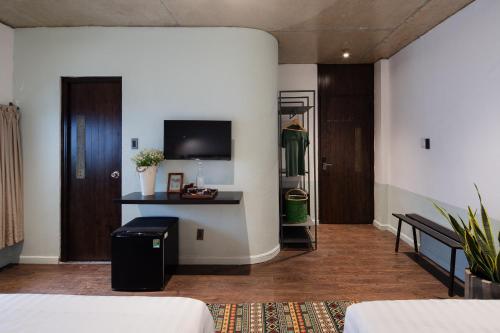 a room with two beds and a tv on a wall at The Note Dalat in Da Lat
