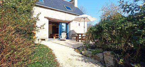 a white cottage with an umbrella and a table at La Ferme du Père in Kermorocʼh