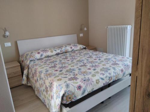 a bedroom with a bed with a floral comforter at Danilo Apartments in Baveno