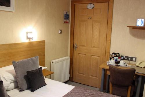 a hotel room with a bed and a desk and a door at Station Hotel And Restaurant in Melrose