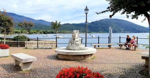 two people sitting on benches near a body of water at Danilo Apartments in Baveno