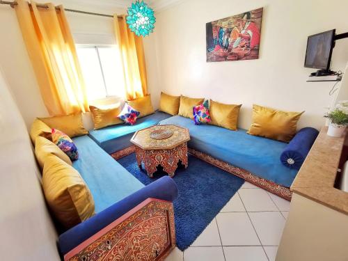 ein Wohnzimmer mit einem blauen Sofa und einem Tisch in der Unterkunft Reta-Inn Martil Beach in Martil