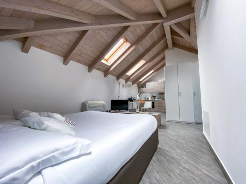 1 dormitorio con cama blanca grande y techo de madera en La Corte del Gallo, en Gallarate