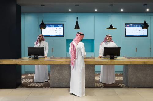 two men standing at a desk with two computers at Ibis Jeddah Malik Road in Jeddah