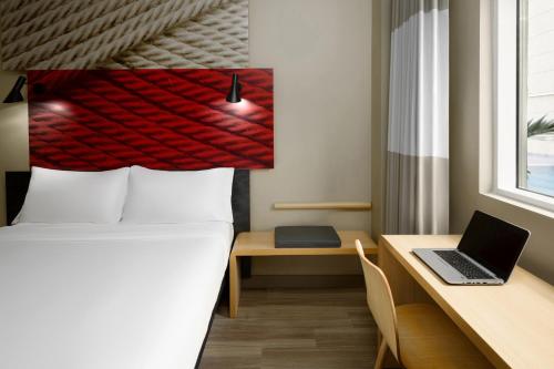 a bedroom with a bed and a desk with a laptop at Ibis Jeddah Malik Road in Jeddah