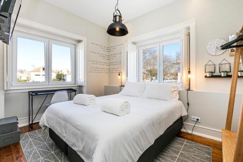 a bedroom with a large bed with white sheets and windows at Sweet Spot @ Beach in Estoril
