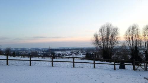 a snow covered field with a fence and trees at De Rieke in Ronse