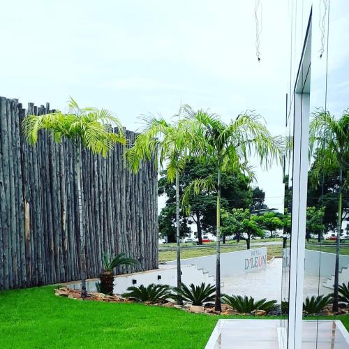 a fence with palm trees in front of a building at Hotel D'Leon in Gurupi
