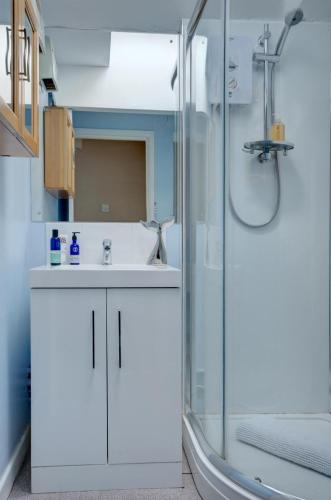 a bathroom with a white sink and a shower at Walkers Court By Treetop Property in Cirencester