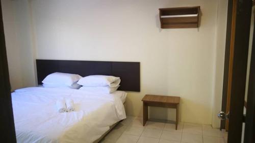 Schlafzimmer mit einem Bett mit weißer Bettwäsche und einem Tisch in der Unterkunft Pangkor staycation apartment in Pulau Pangkor