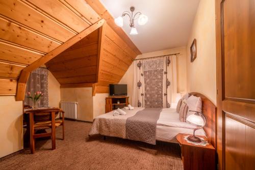 a bedroom with a bed and a table and a television at Willa u Zwijaczy in Zakopane