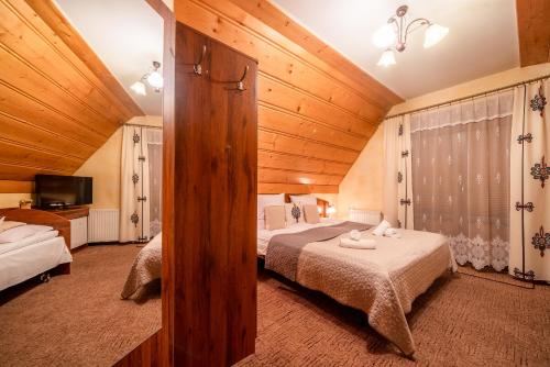 a bedroom with two beds in a room with wooden ceilings at Willa u Zwijaczy in Zakopane