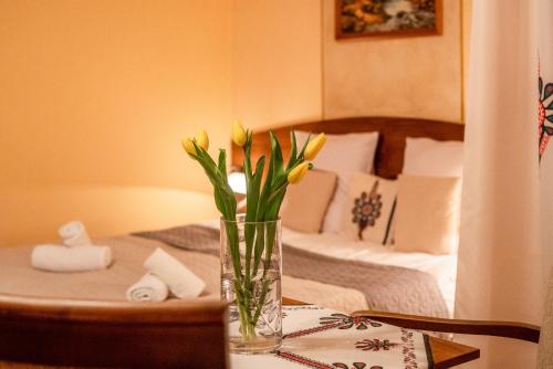a vase with yellow flowers on a table in front of a bed at Willa u Zwijaczy in Zakopane