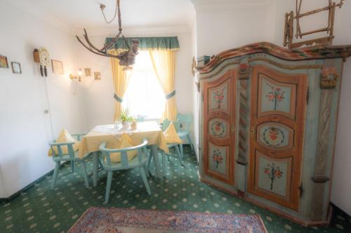 a dining room with a table and a wooden cabinet at Hotel Garni Hubertus-Nostalgie & Charme in Fulpmes