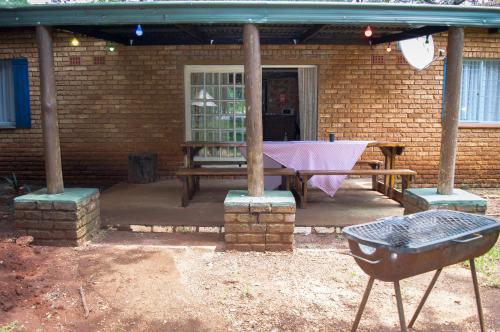 a patio with a picnic table and a brick wall at Shangrila-innibos Country Lodge in Hartbeespoort