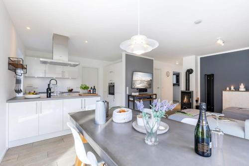 a kitchen and living room with a table with a bottle of wine at lovely&cool STIL-HAUS in Fehmarn
