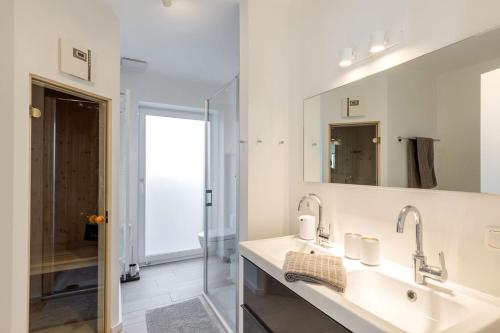 a white bathroom with a sink and a mirror at lovely&cool STIL-HAUS in Fehmarn